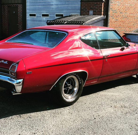 A red car is parked in front of a garage door