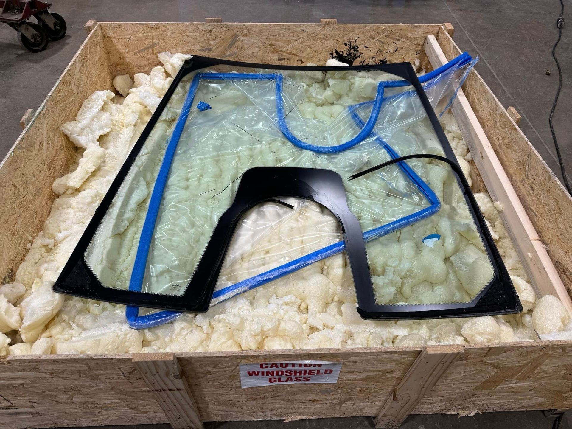 A wooden box filled with foam and broken windshields.