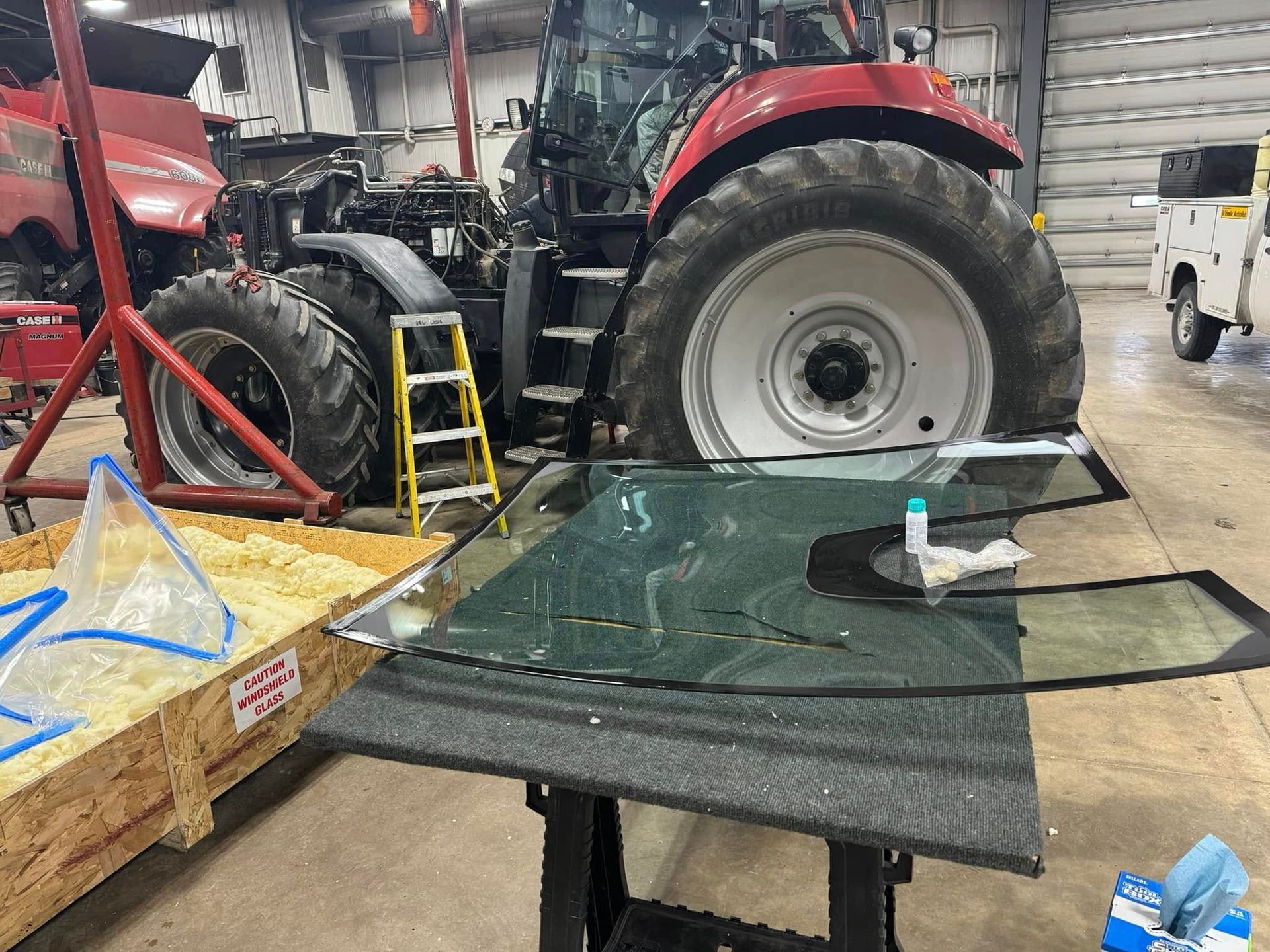 A tractor is sitting in a garage next to a table with a piece of glass on it.