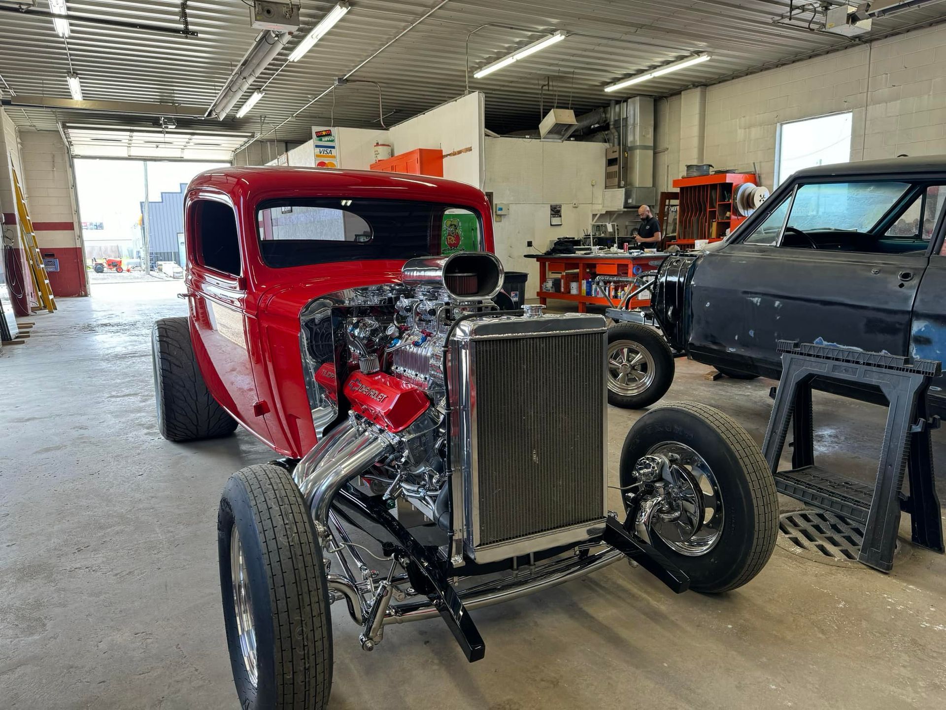 A red hot rod is parked in a garage.