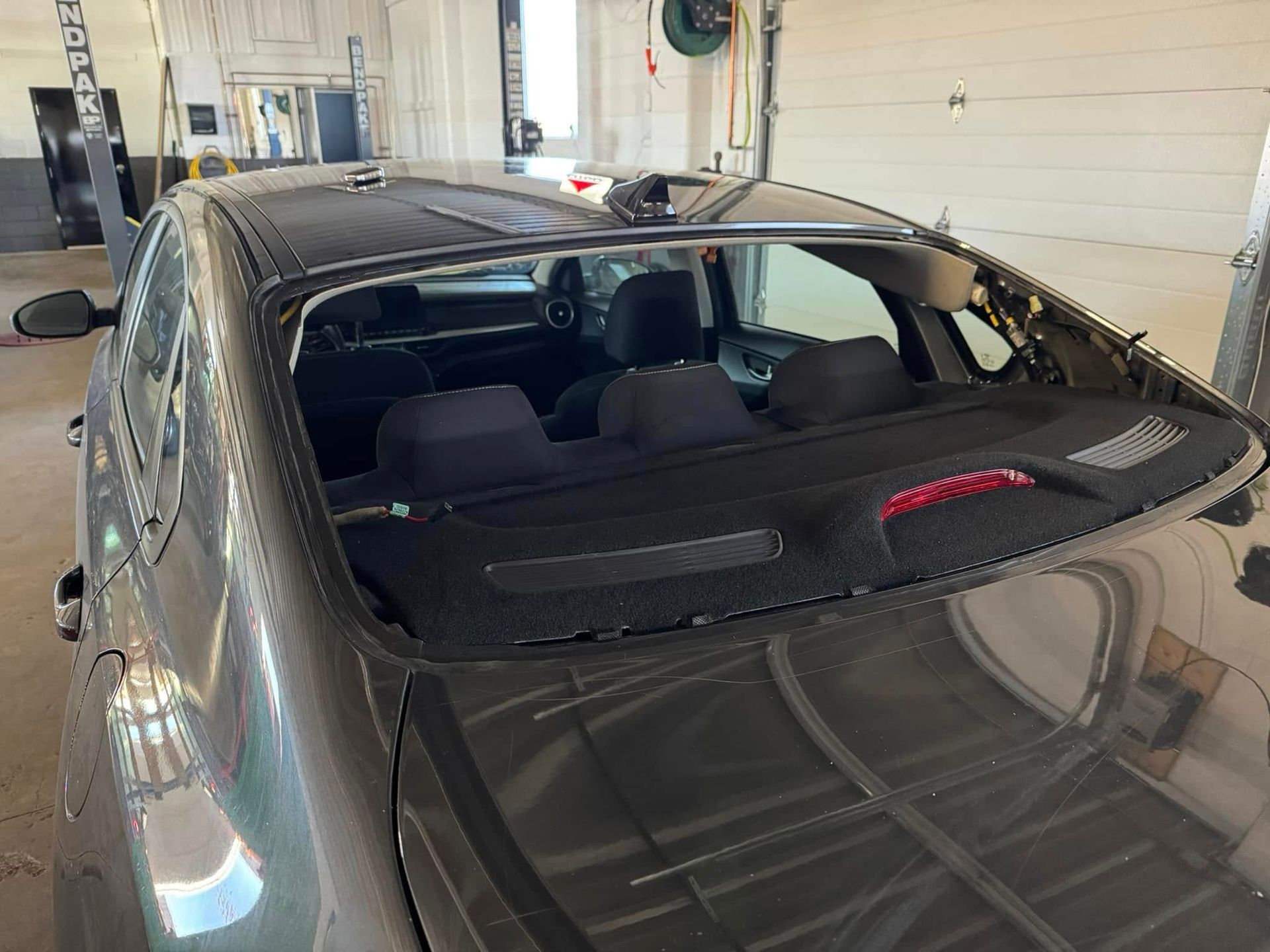 A car with a broken windshield is parked in a garage.