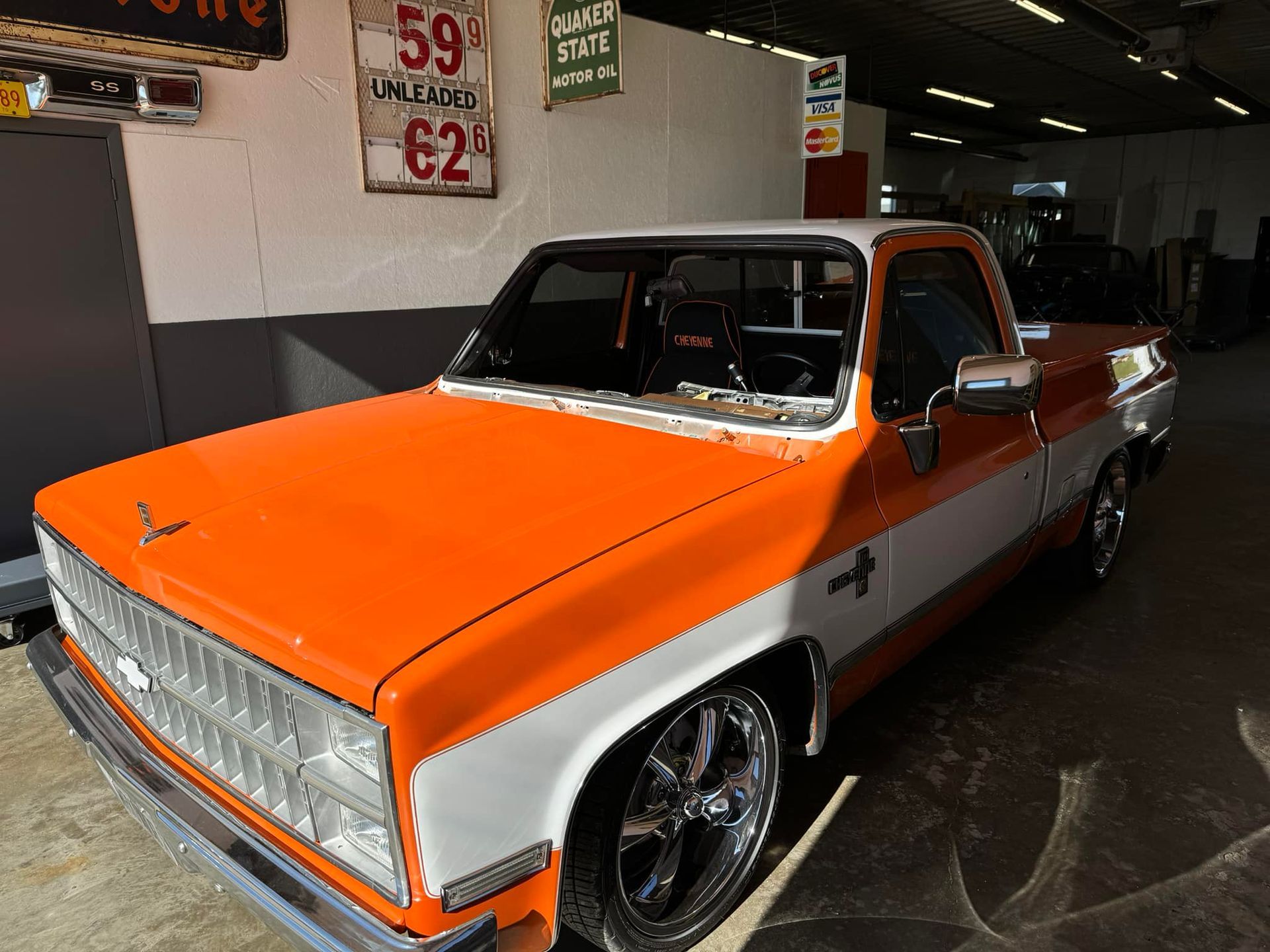 An orange and white truck is parked in a garage.