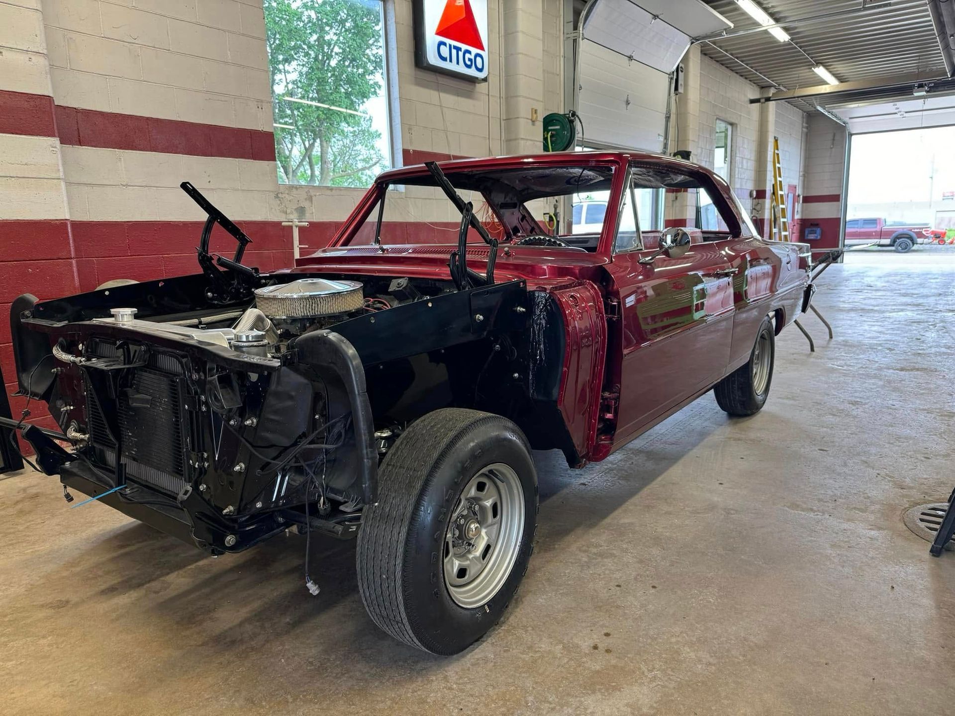 A red car is being restored in a garage.