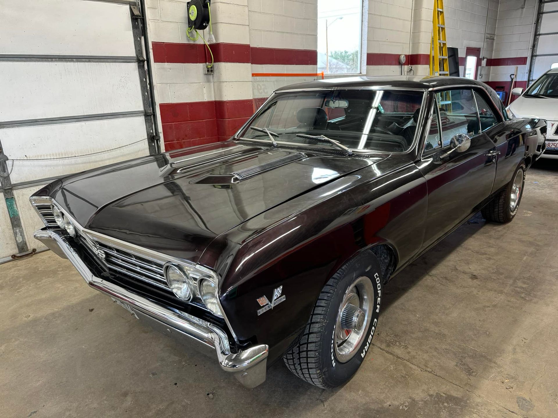 A black muscle car is parked in a garage.