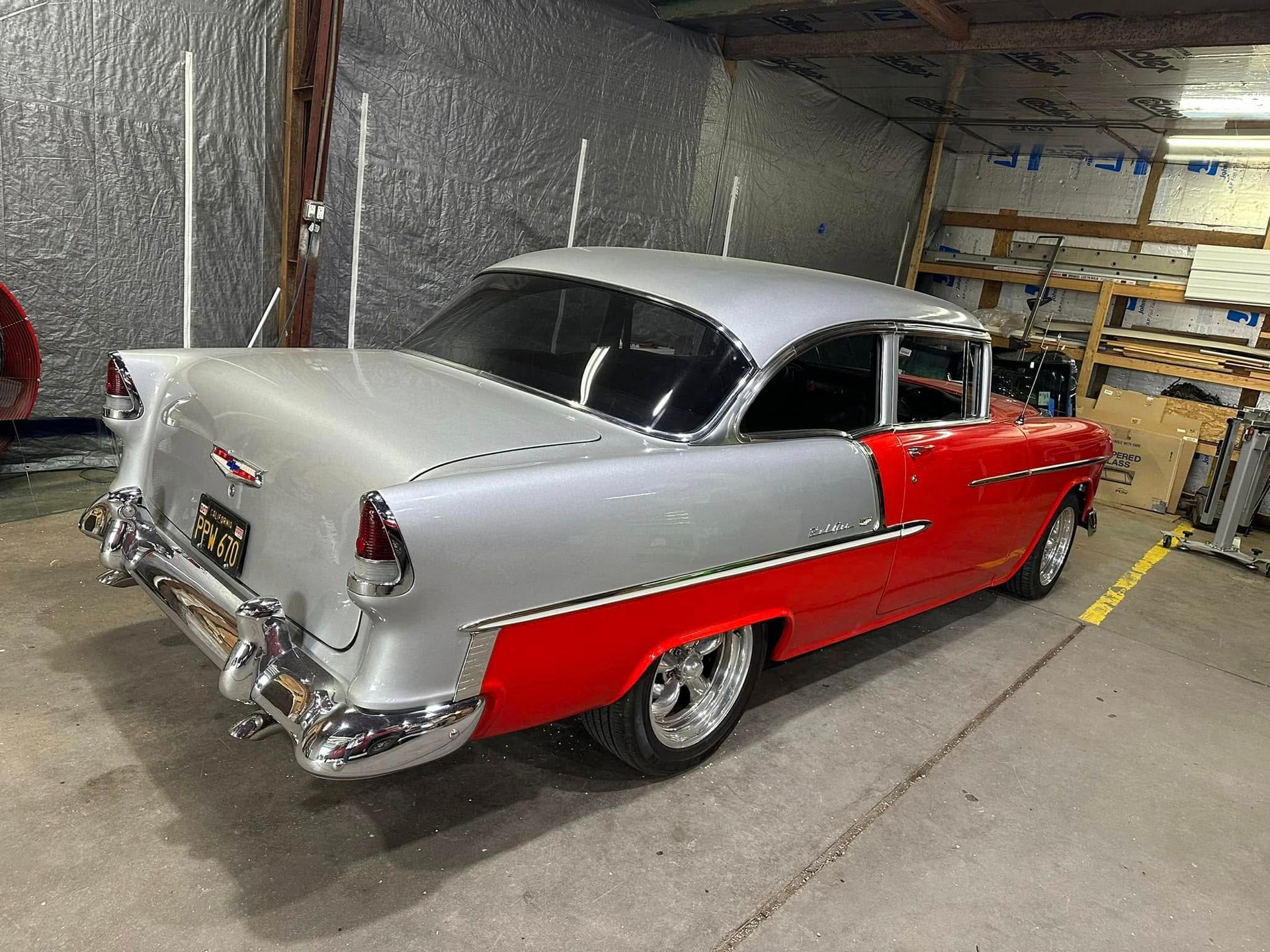 A red and silver car is parked in a garage.