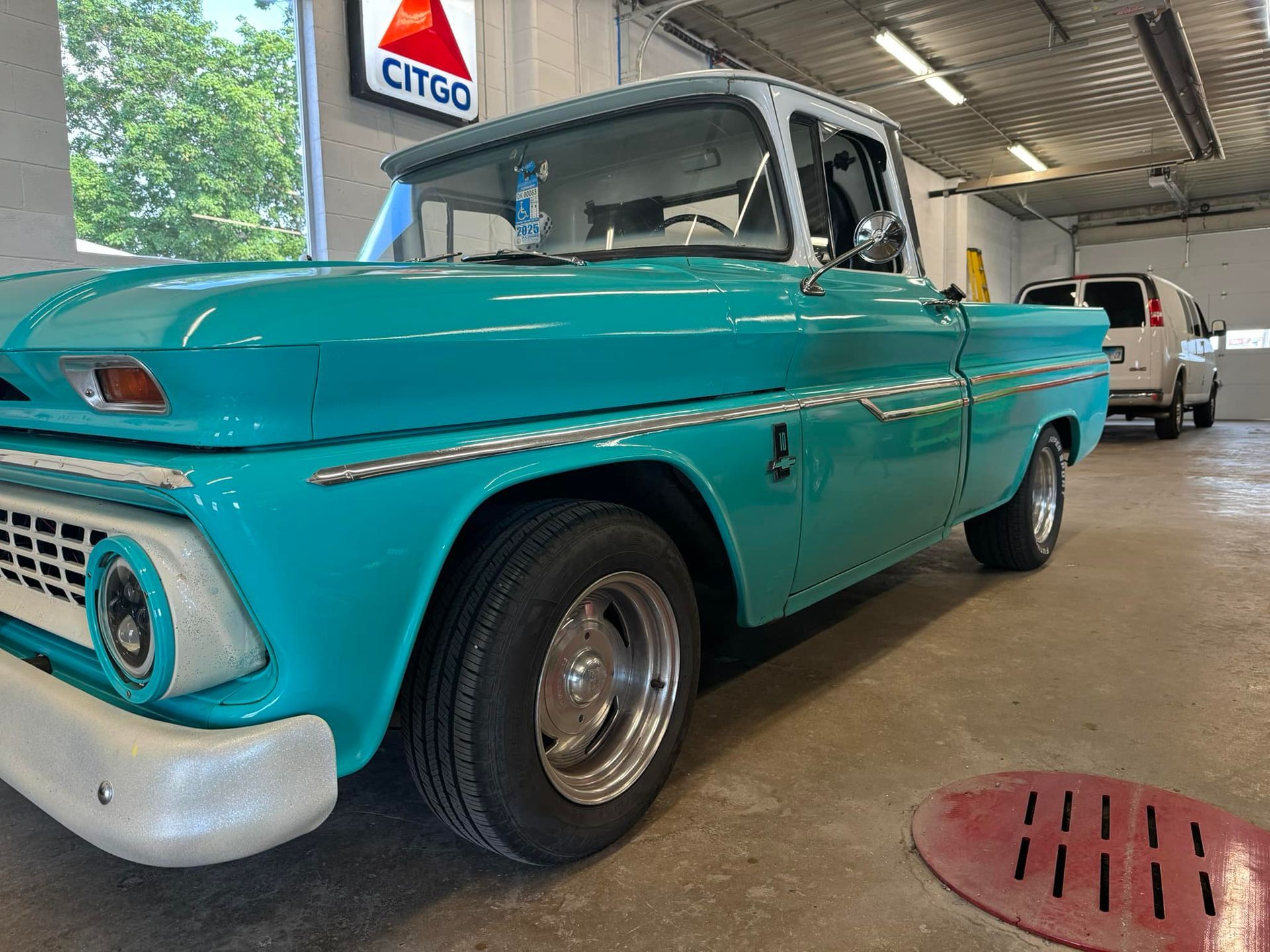 A blue pickup truck is parked in a garage next to a citigo sign.