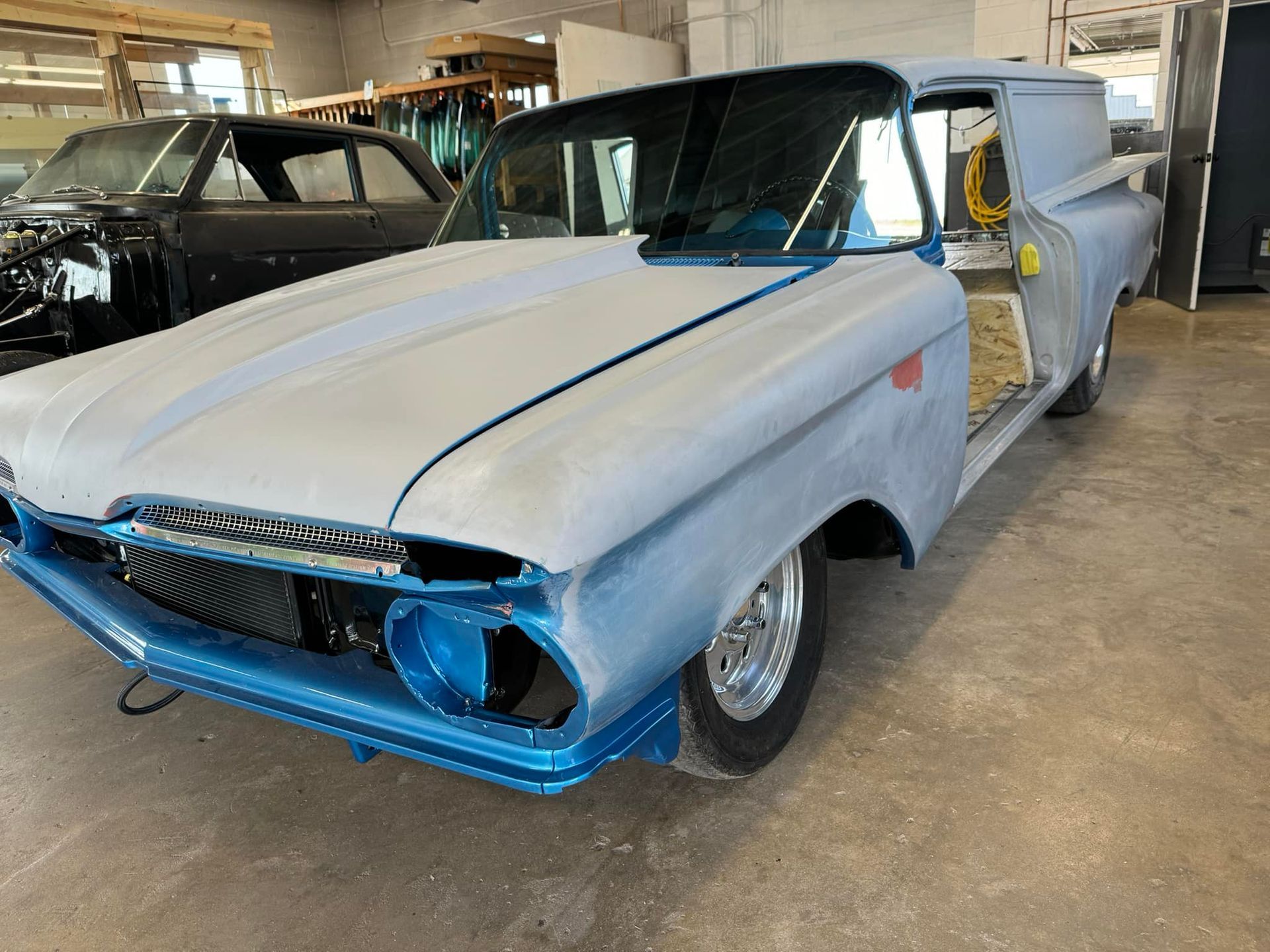 A blue and white car is parked in a garage.