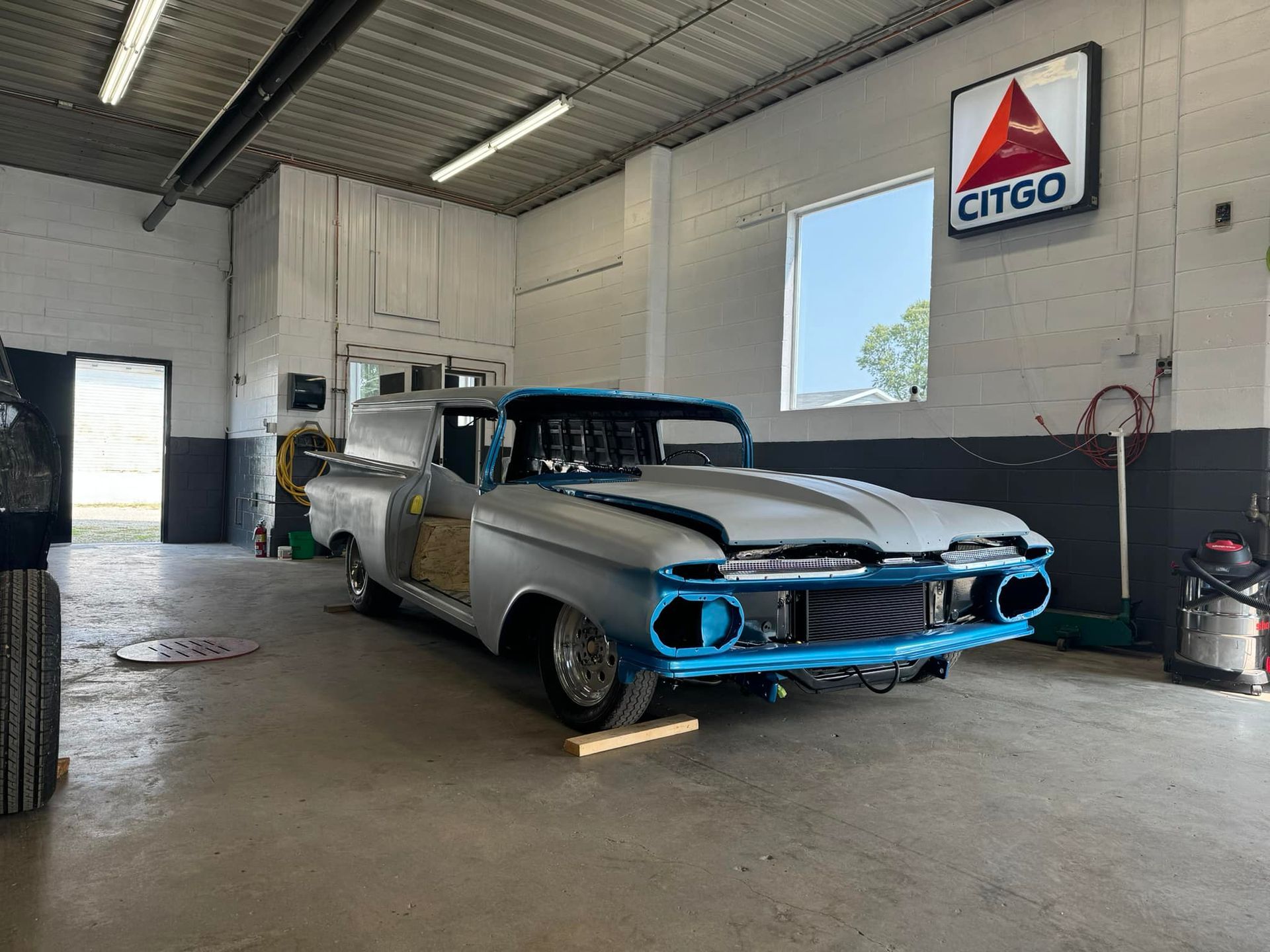 A white and blue truck is parked in a garage next to a citroën sign.