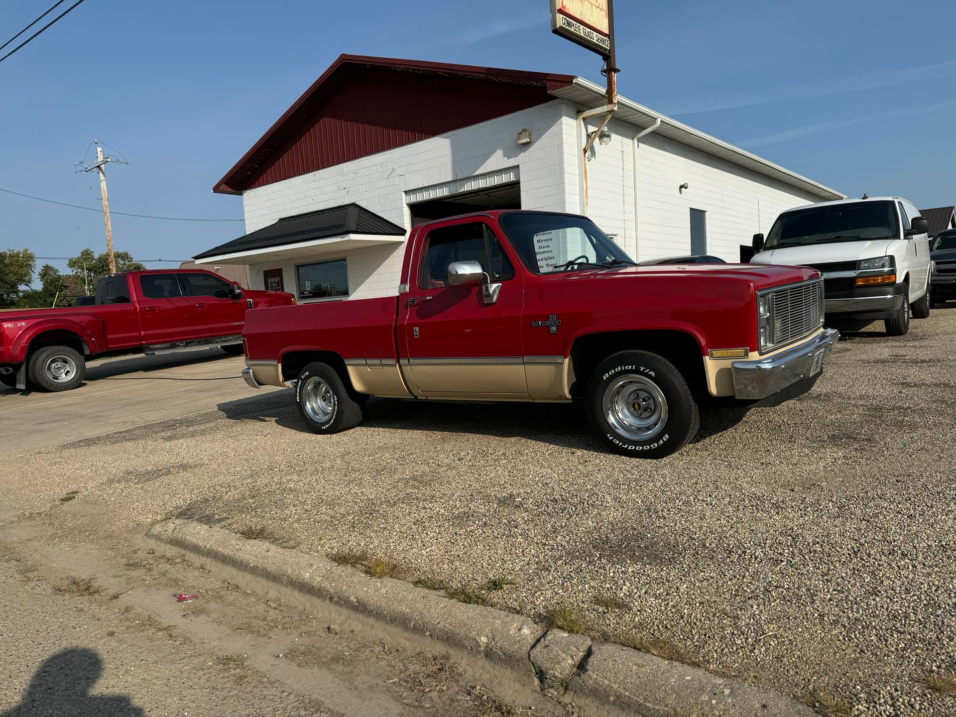 A red truck is parked in front of a white building.
