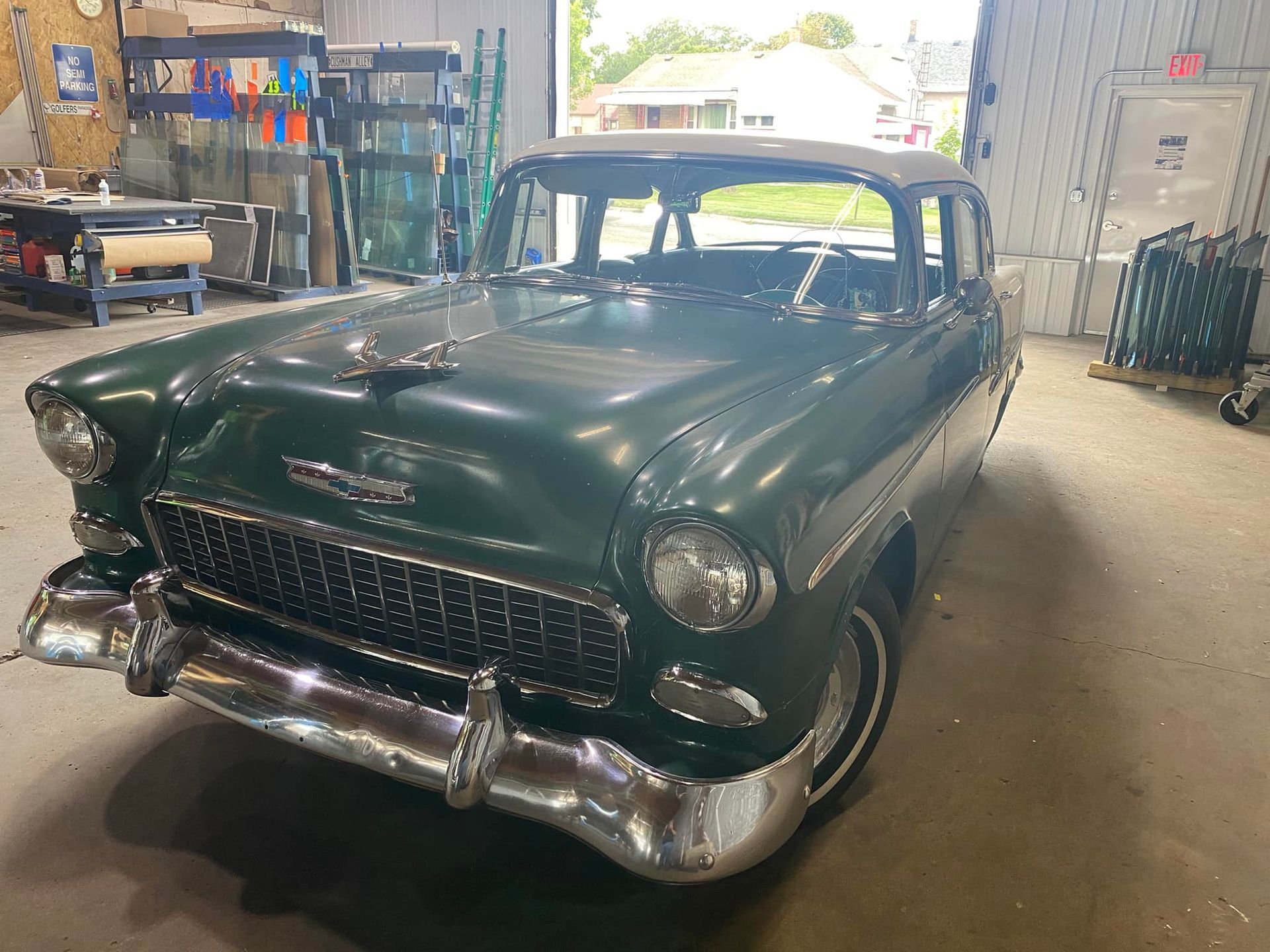 An old green car is parked in a garage.