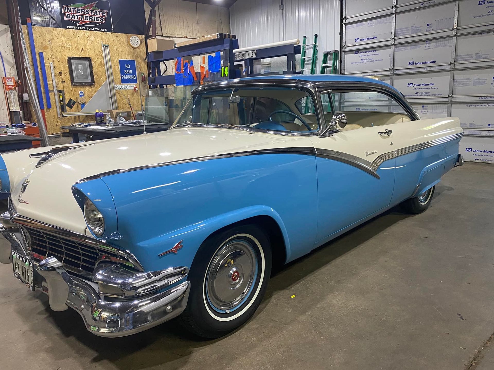 A blue and white classic car is parked in a garage.