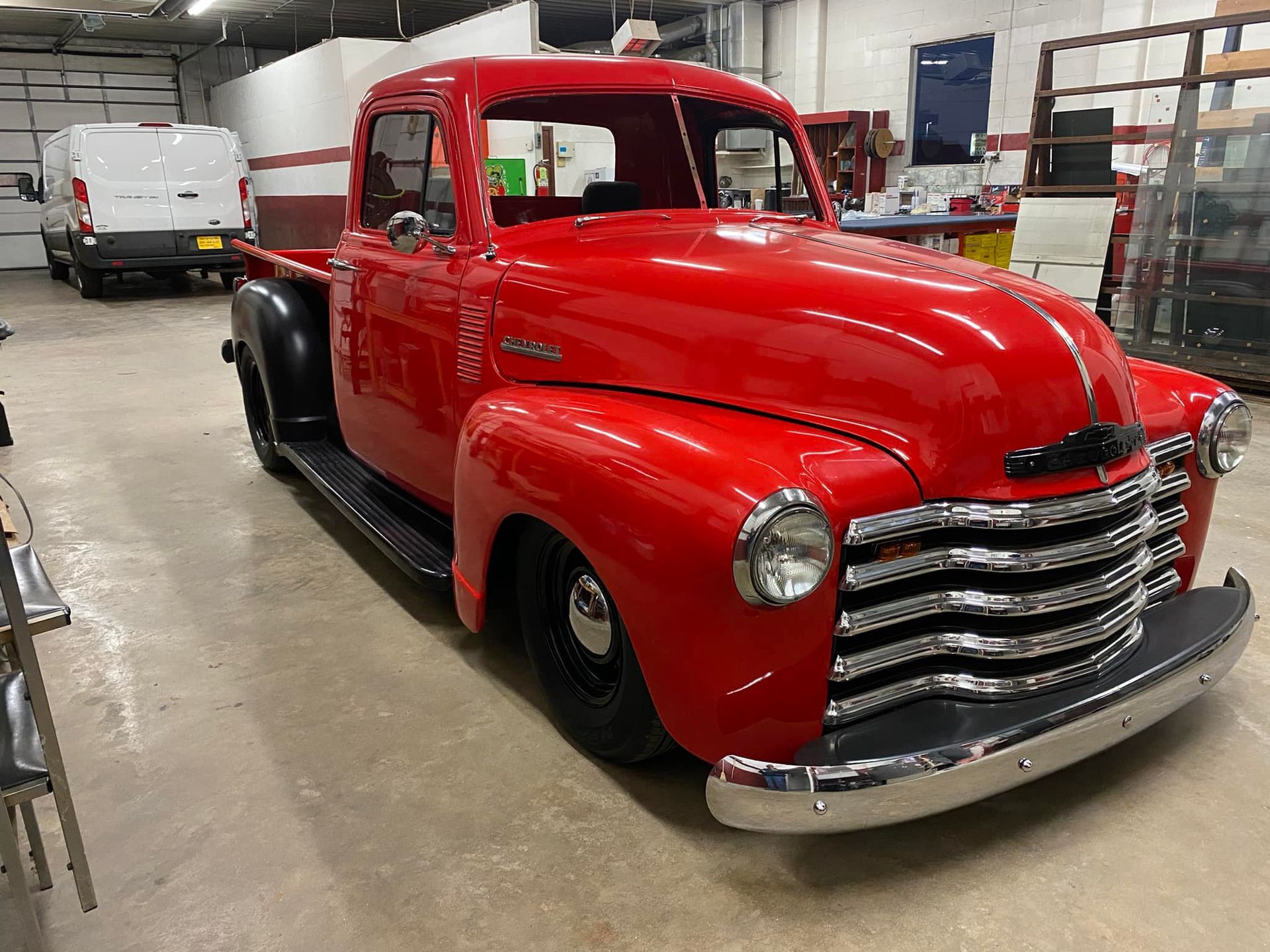 A red chevrolet truck is parked in a garage.