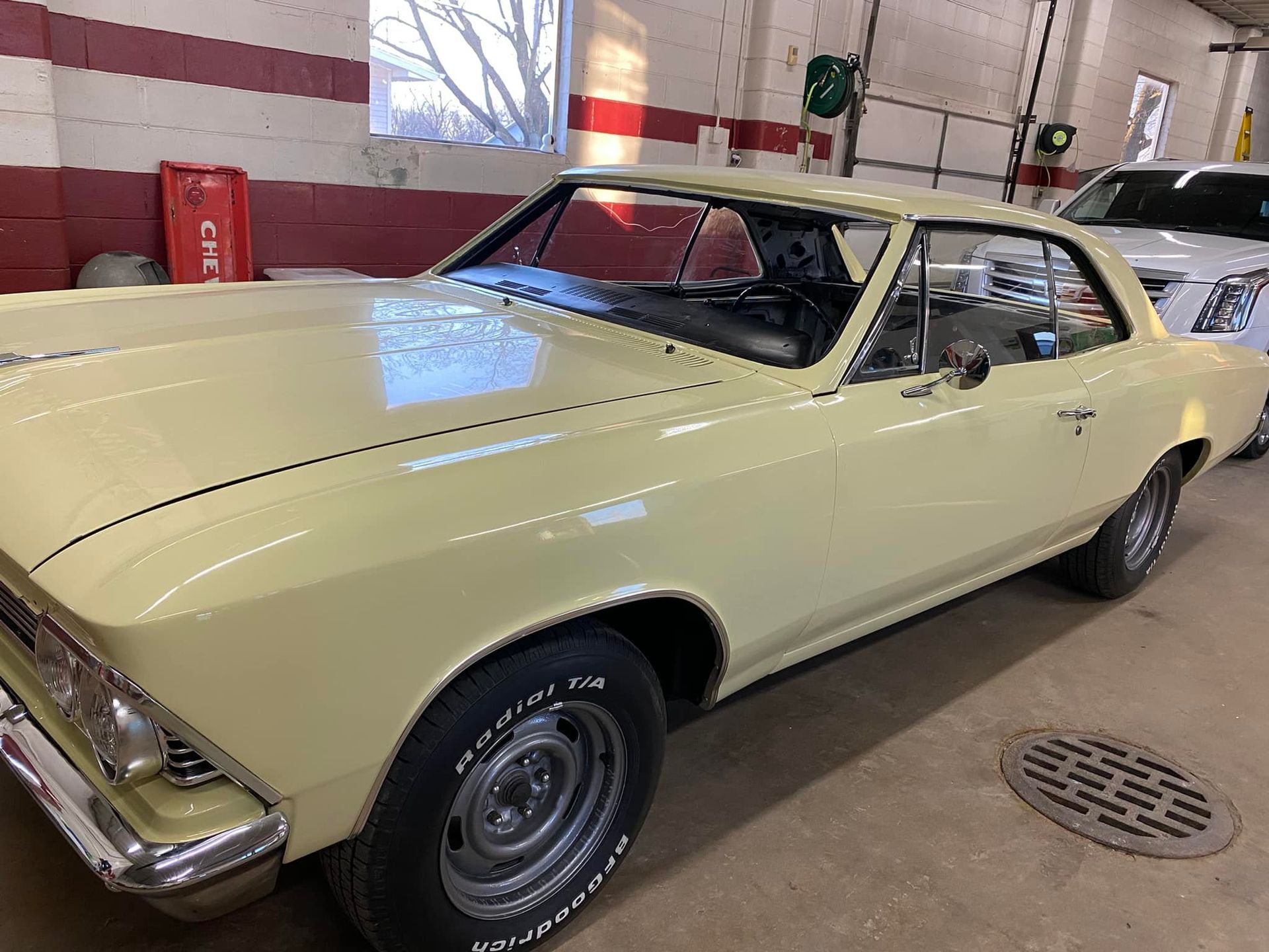 A yellow car is parked in a garage next to another car.
