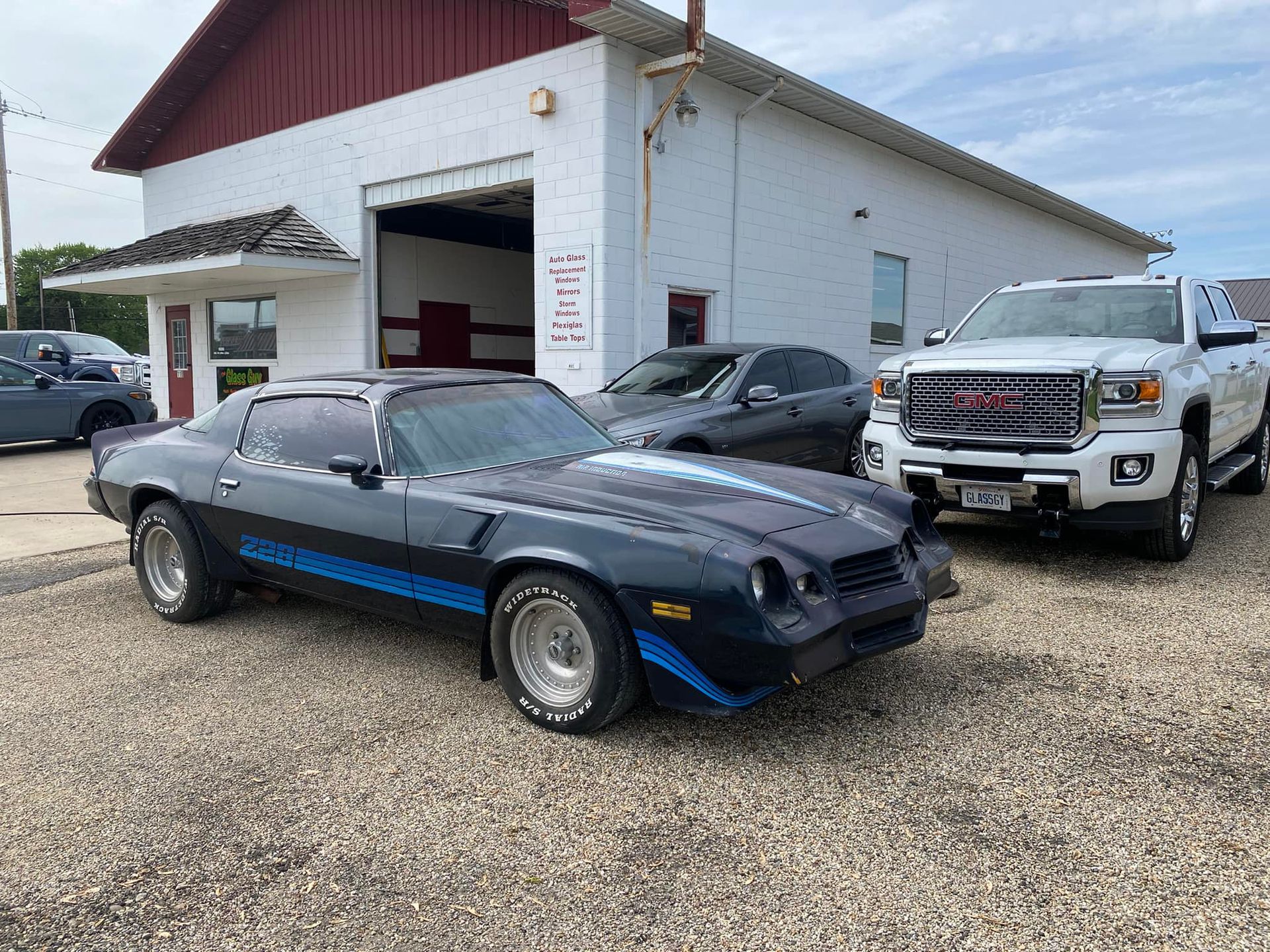 A black car and a white truck are parked in front of a garage.
