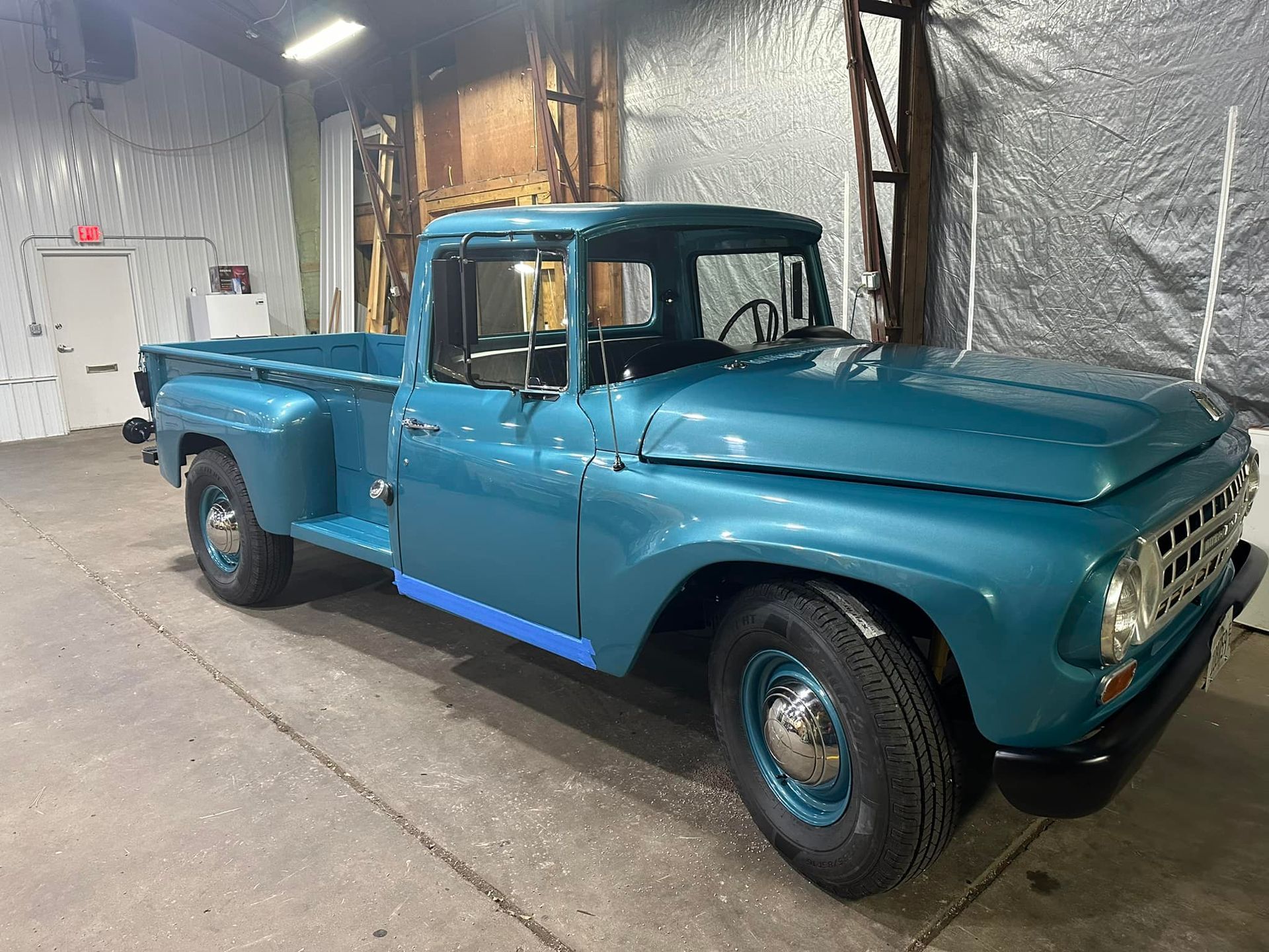 A blue pickup truck is parked in a garage.