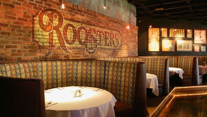 Booths in a restaurant with a brick wall featuring a decorative 
