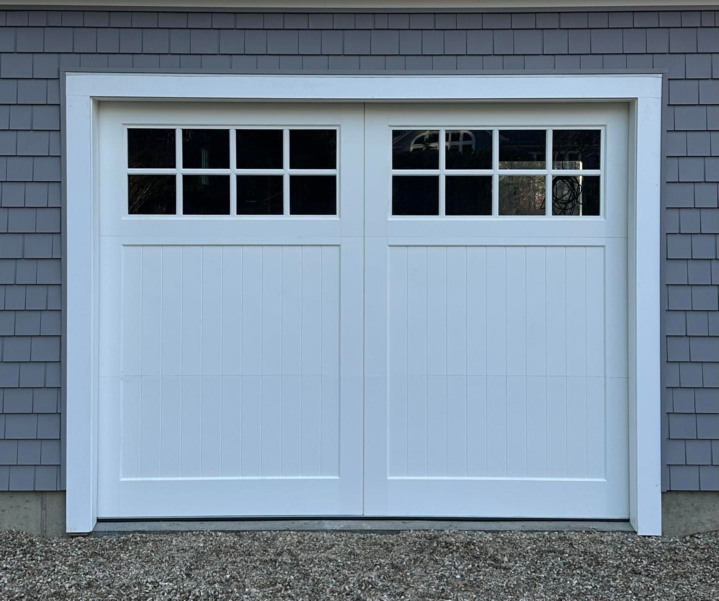 A white garage door with a gray brick wall behind it