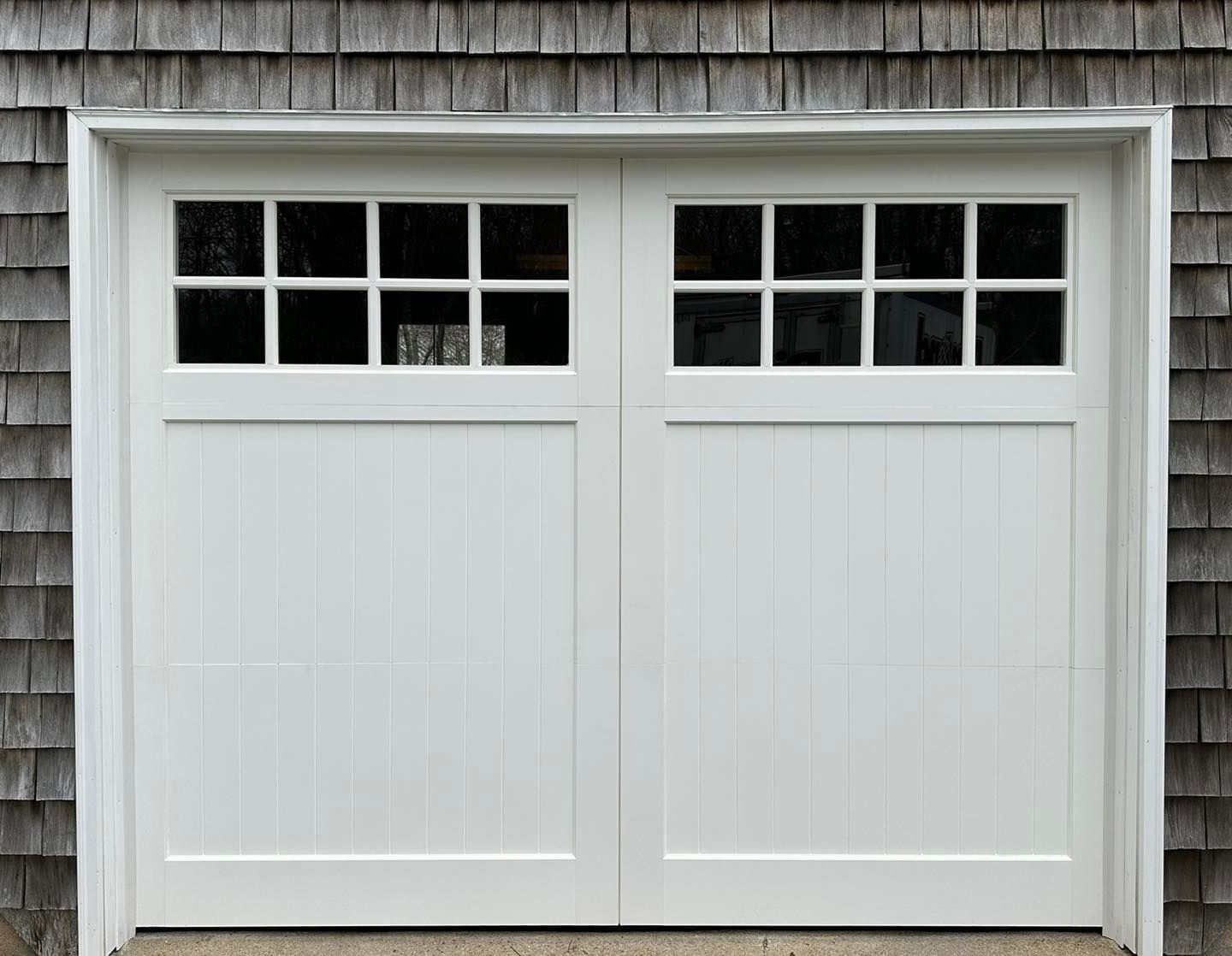 A white garage door with a wooden shingle roof