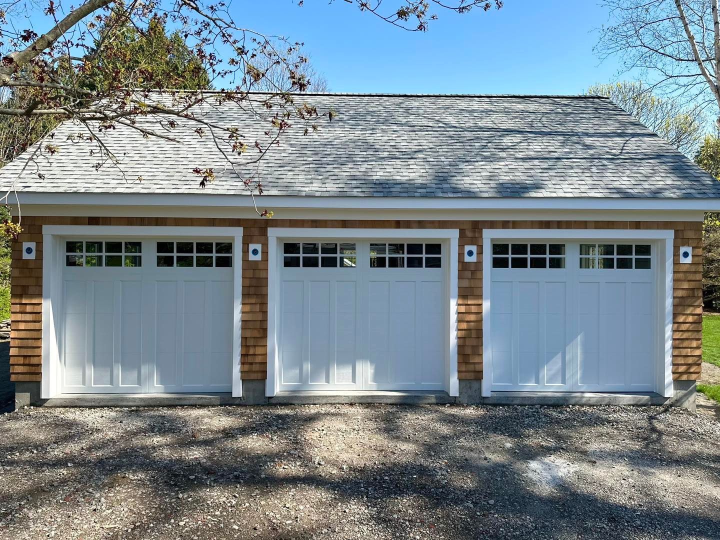 A garage with three white doors and a gray roof