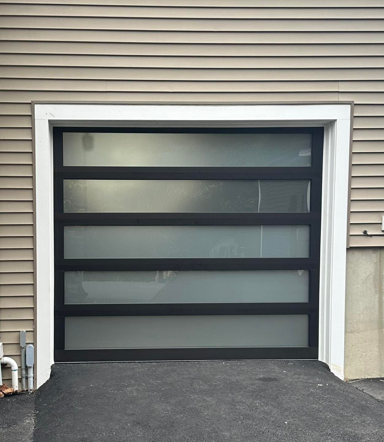 A black garage door with a frosted glass panel