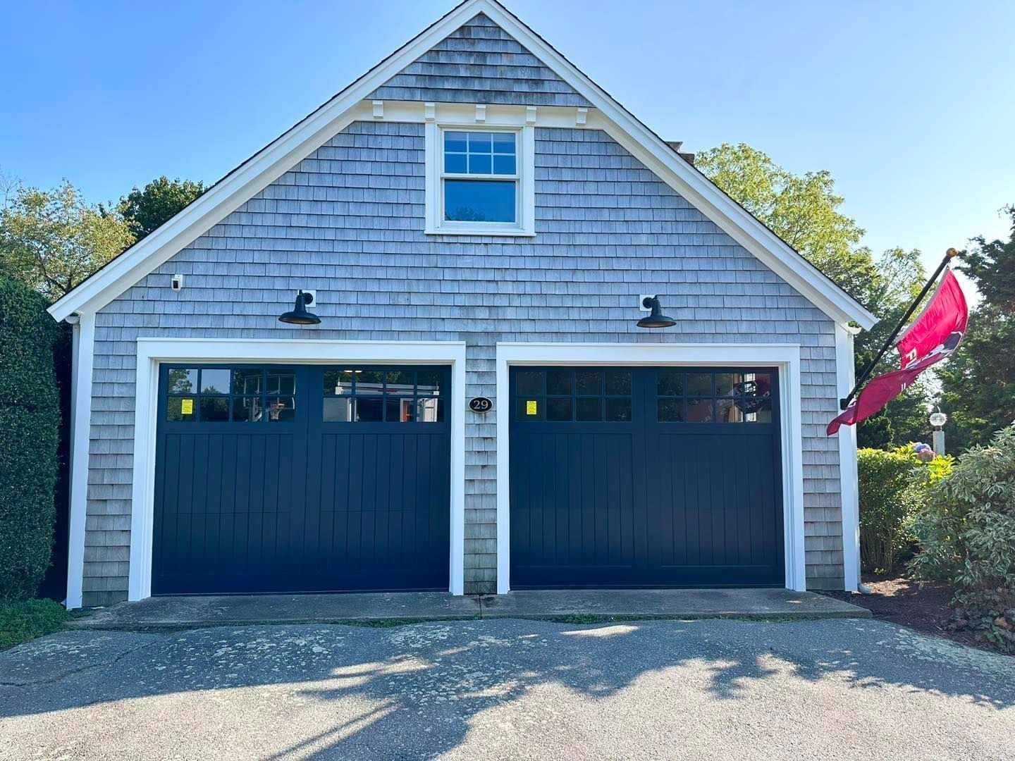 A garage with two black garage doors and a pink flag