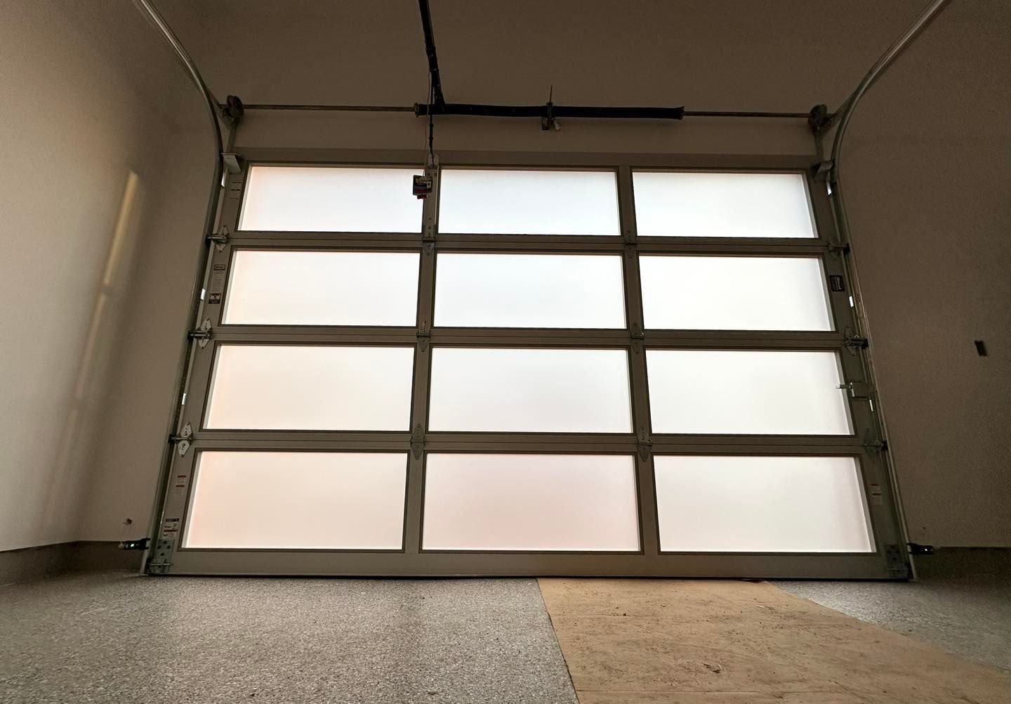 A garage door with a lot of windows is open in a garage