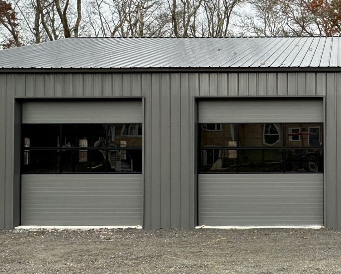 A garage with two garage doors and a black roof