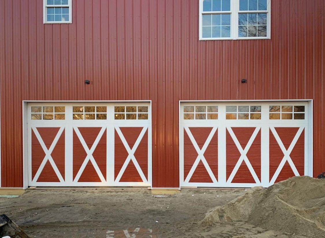 A red barn with white garage doors 