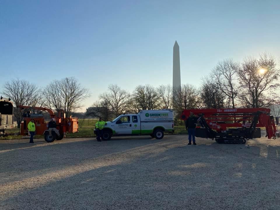 Work vehicles near the Washington Monument. Men in safety vests; clear sky.