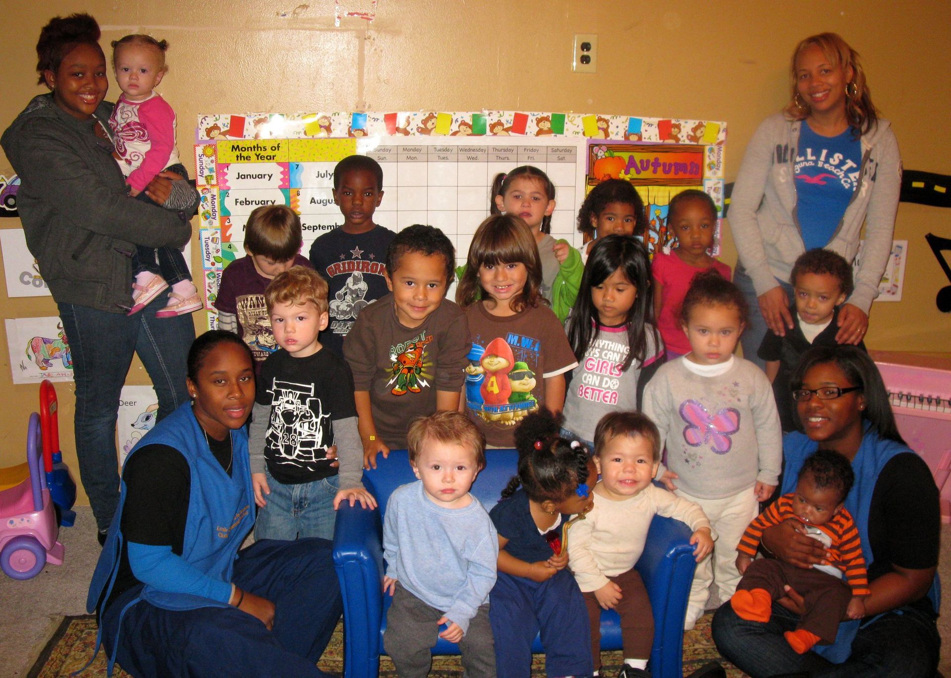 A group of children are posing for a picture and one of them is wearing a shirt that says believe.