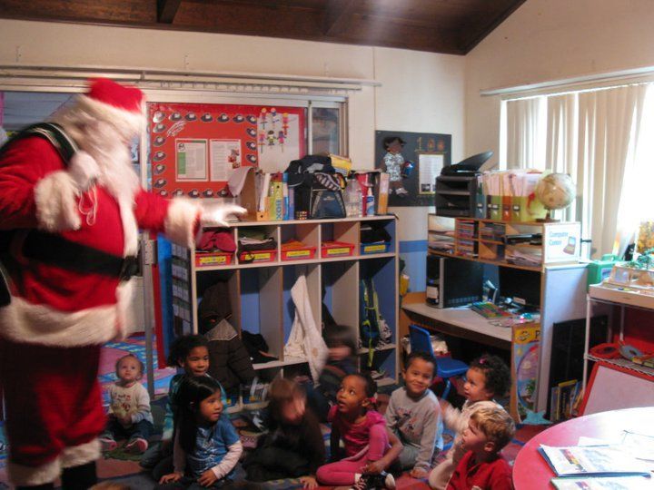 Santa claus is standing in front of a group of children.
