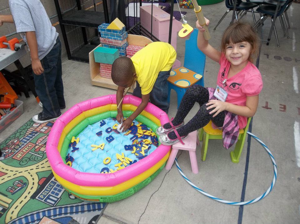 A boy and a girl are playing with letters in an inflatable pool.
