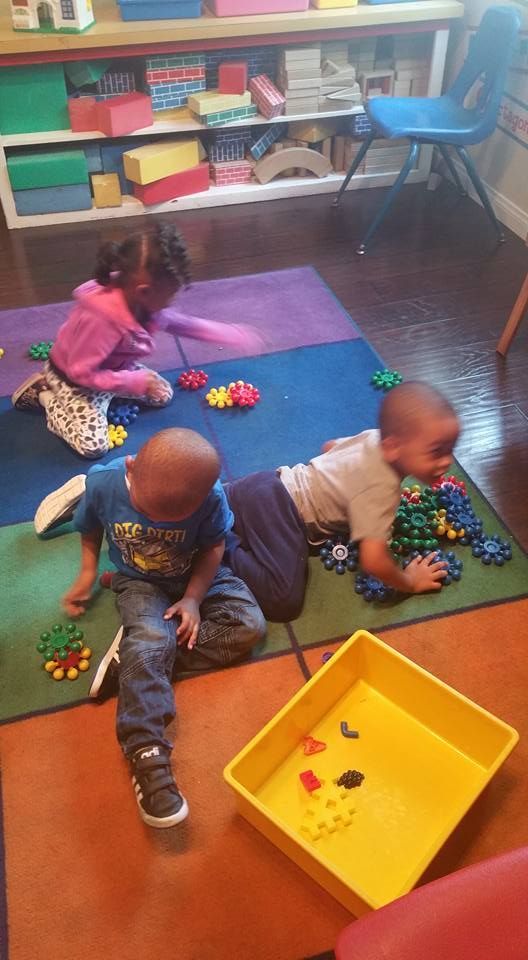 A group of children are playing with toys on the floor.