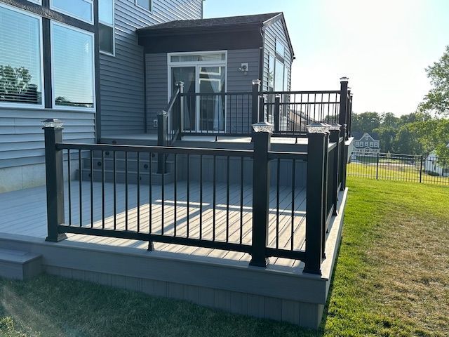 Composite deck with black railing and attached enclosed porch on a sunny day.