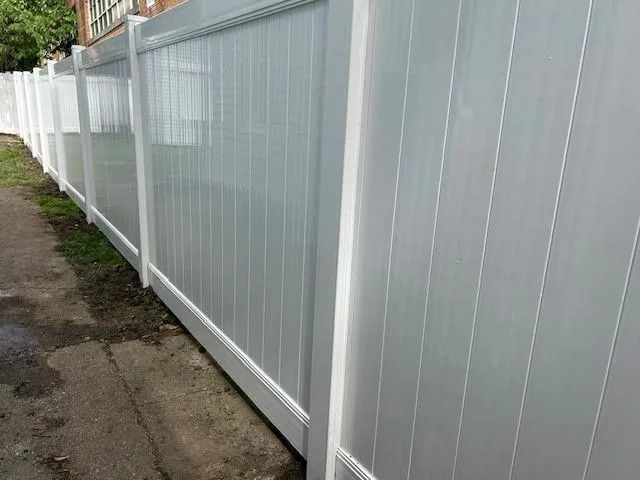 White vinyl privacy fence along a sidewalk.