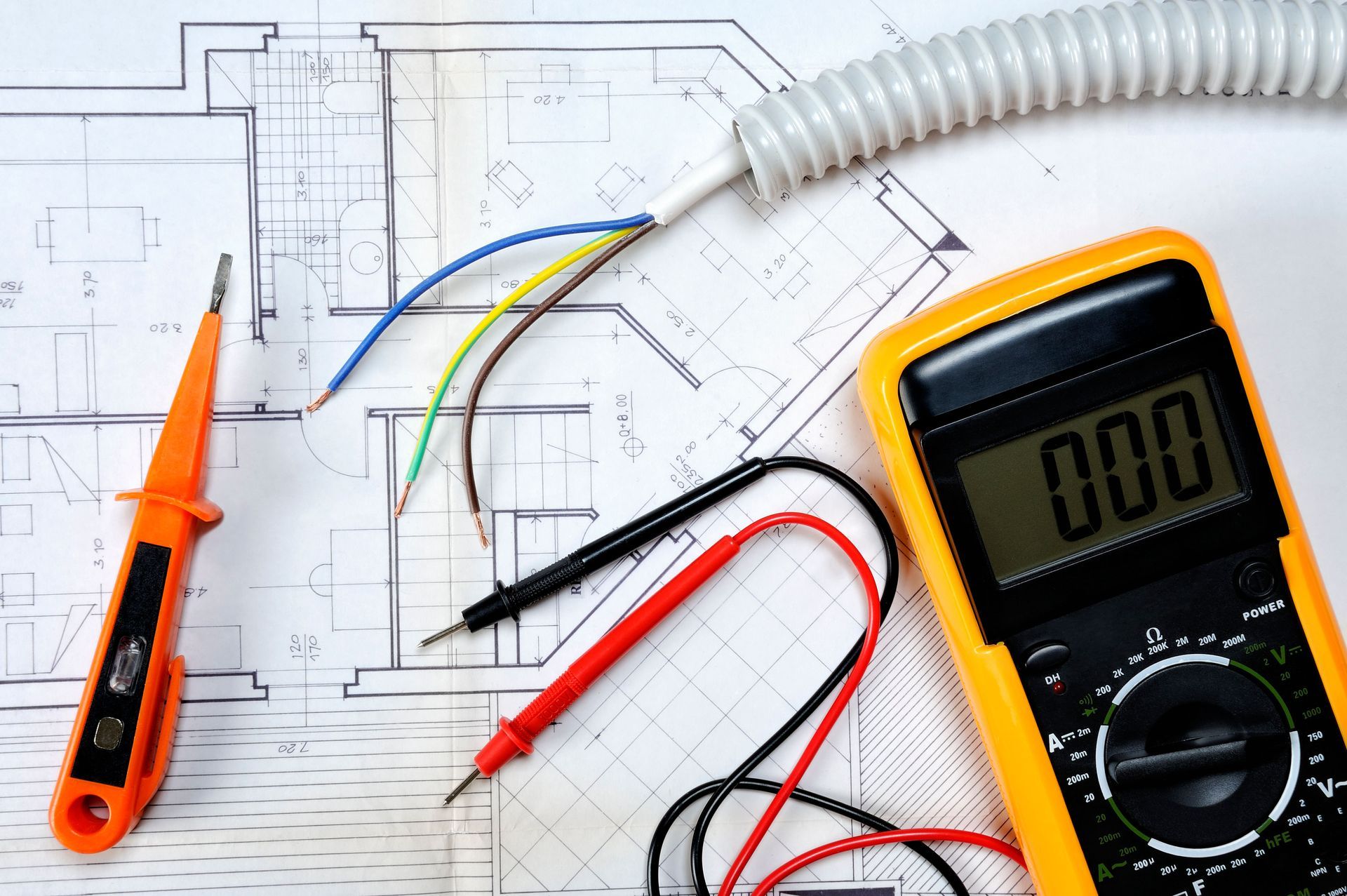 A digital multimeter is sitting on top of a blueprint.