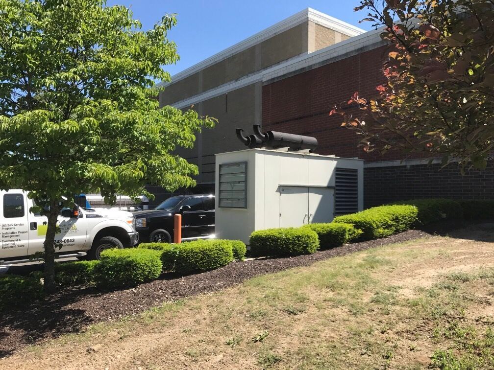A white truck is parked in front of a large building with a generator.