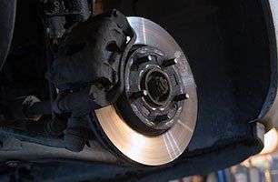 Learn more about brake repairs Car brake rotor and caliper assembly. Close-up view of the brake disc and surrounding components.