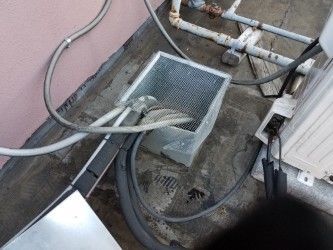 Metal air conditioning components on a rooftop, including a filter box, pipes, and electrical wiring.