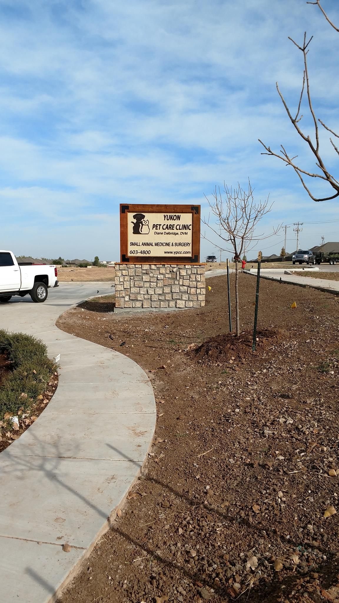 A white truck is parked on the side of the road next to a sign.
