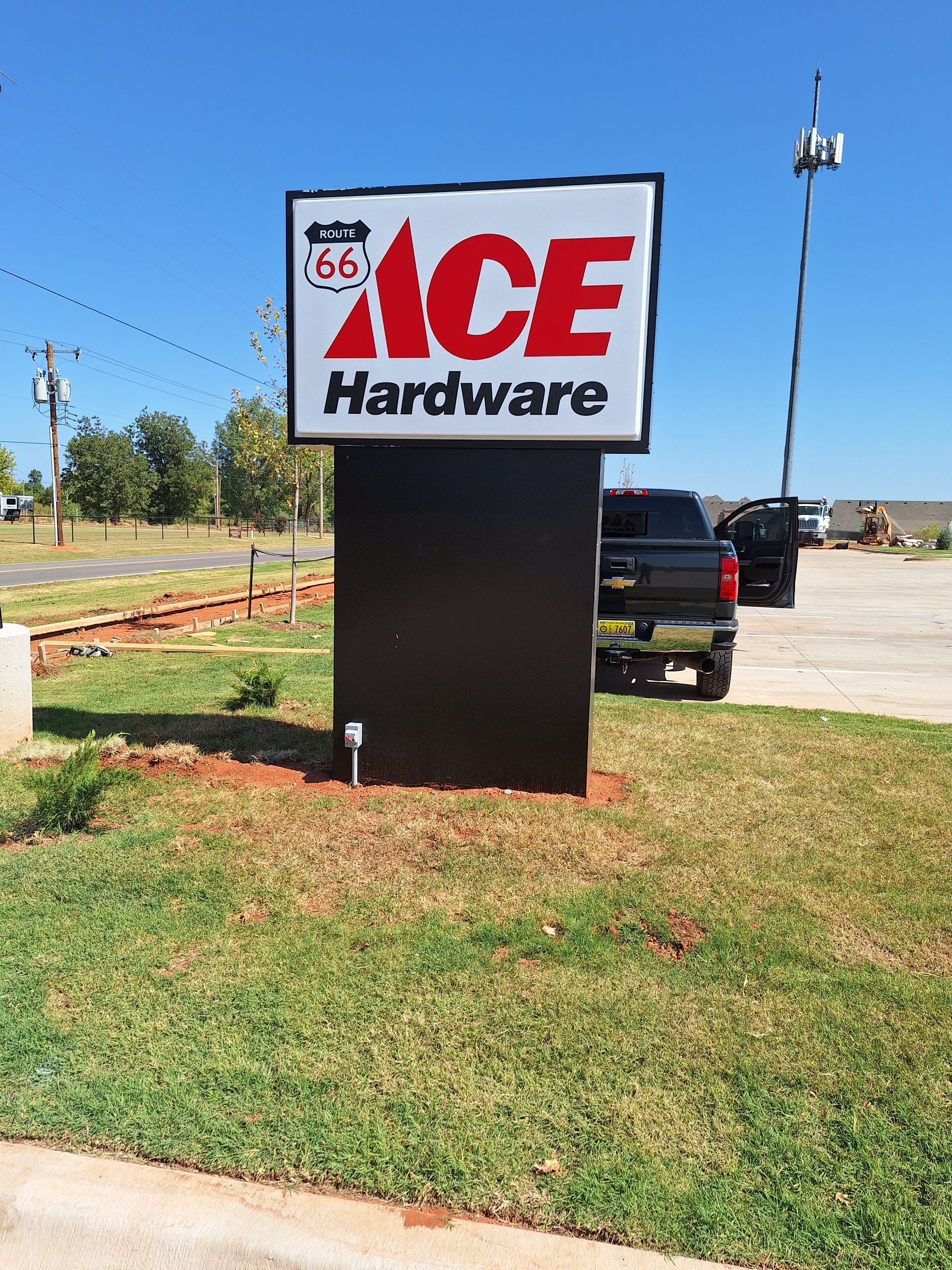 A large sign for ace hardware is sitting in the grass.