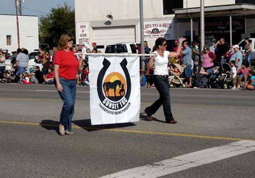 Two women are walking down a street holding a horseshoe flag