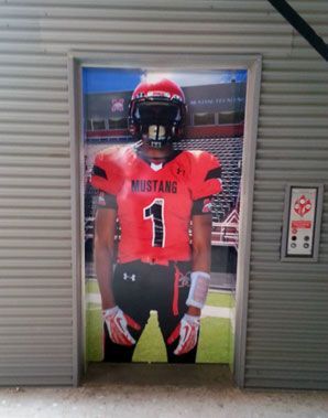 A mustang football player is standing in a doorway