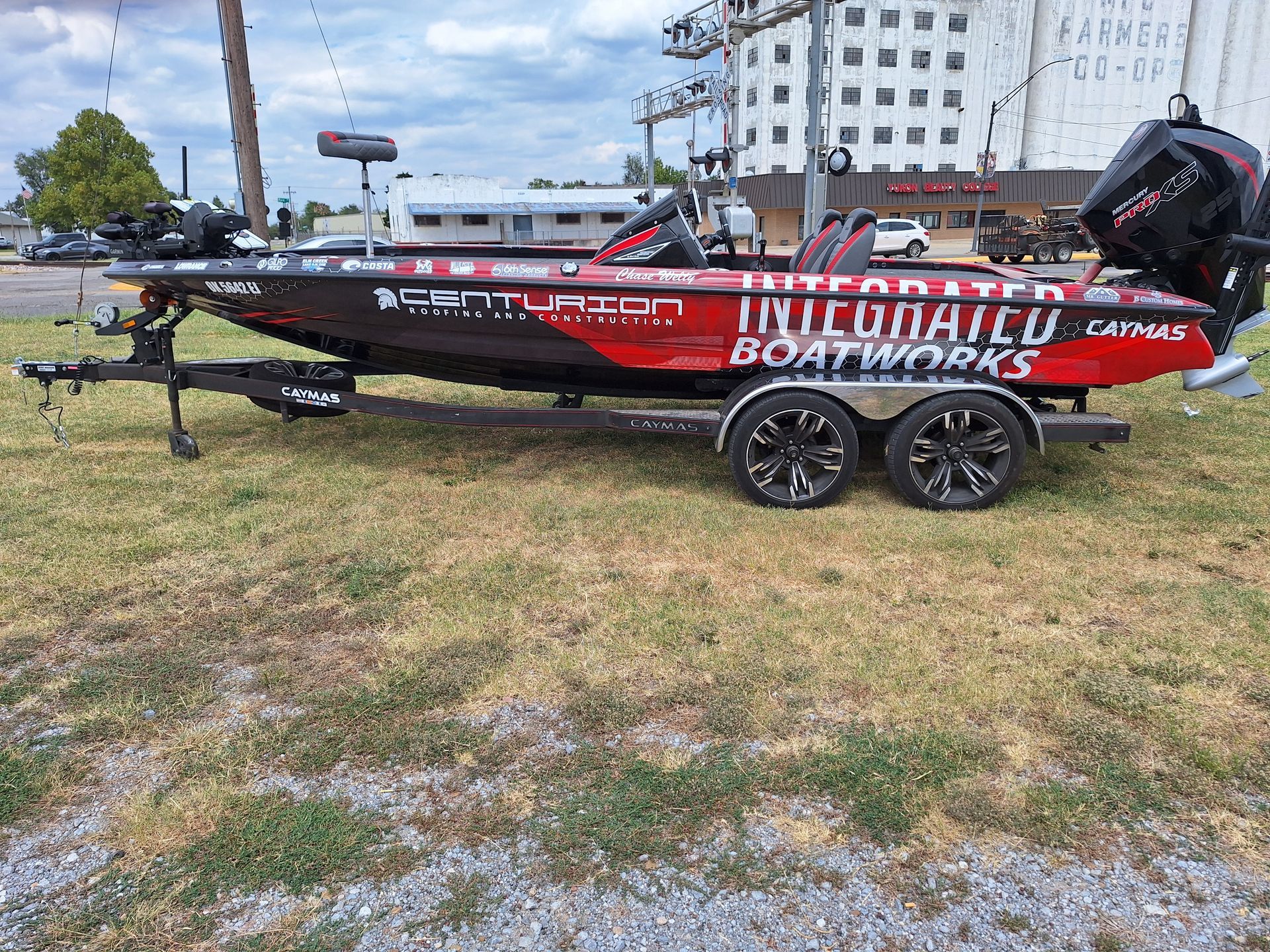 A red and black fishing boat is parked in a grassy field.