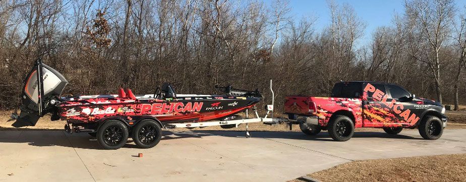 A red truck is towing a red boat on a trailer.