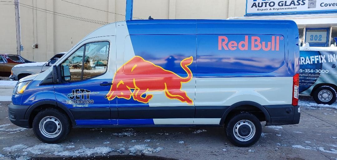A red bull van is parked in front of a building.