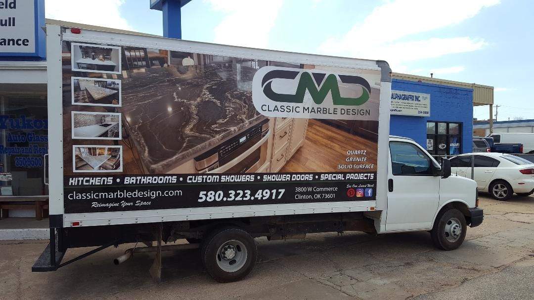 A white truck with a large advertisement on the side is parked in front of a building.