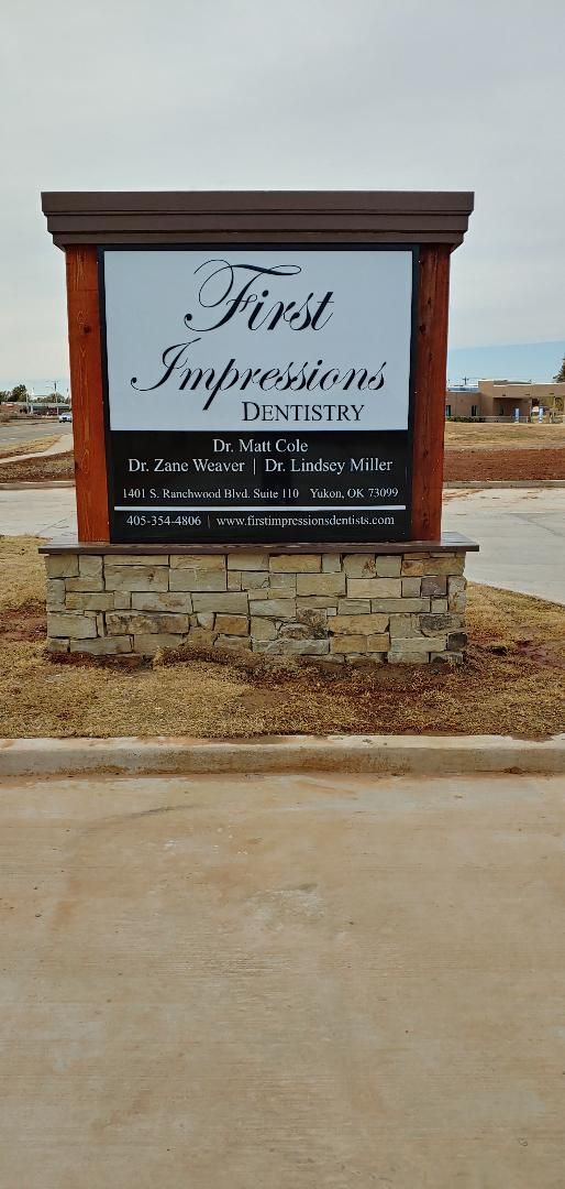 A sign for a dental office is sitting on the side of a road.