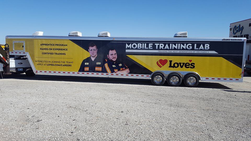 A mobile training lab trailer is parked in a parking lot