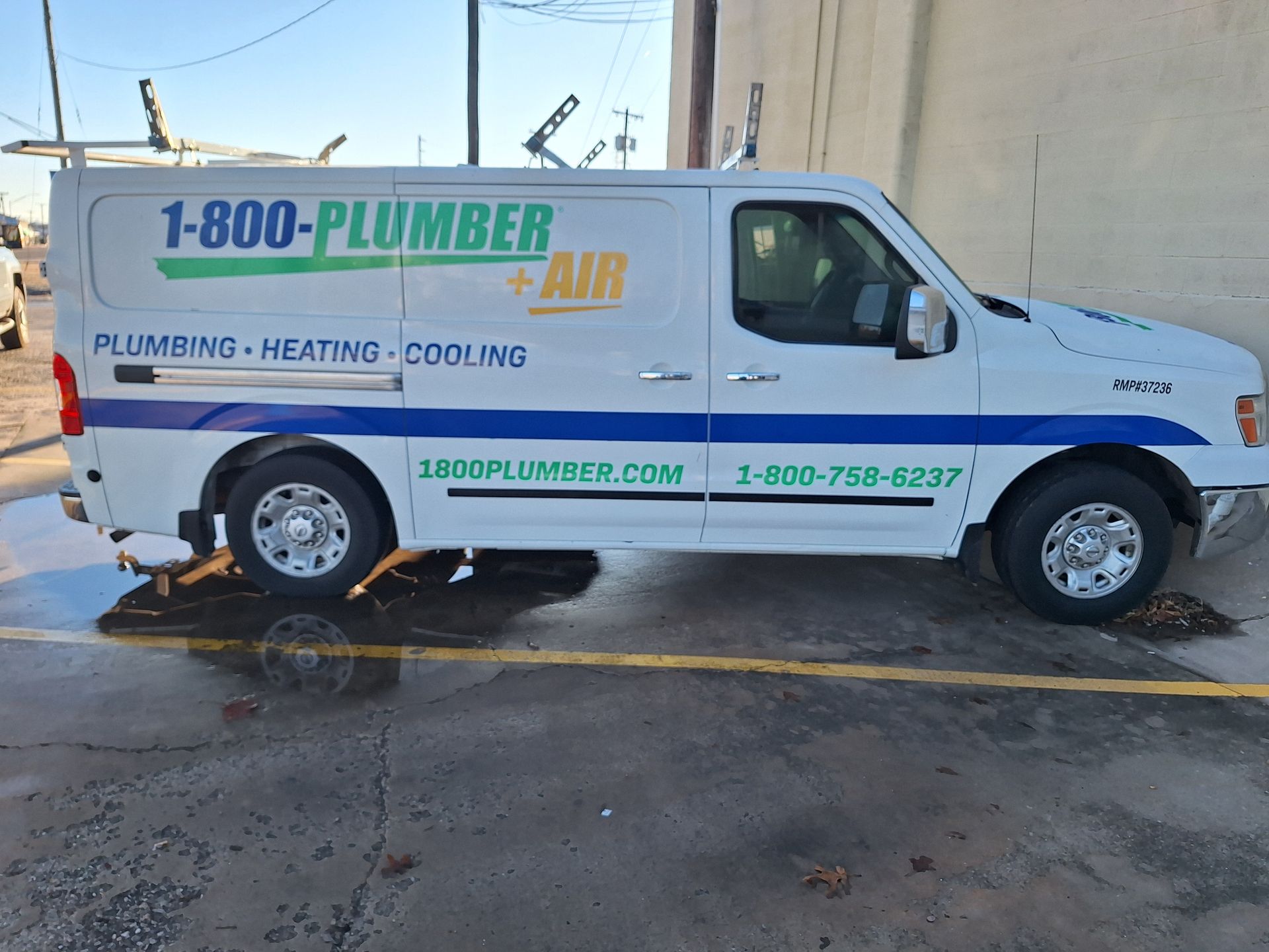 A white plumber van is parked in a parking lot